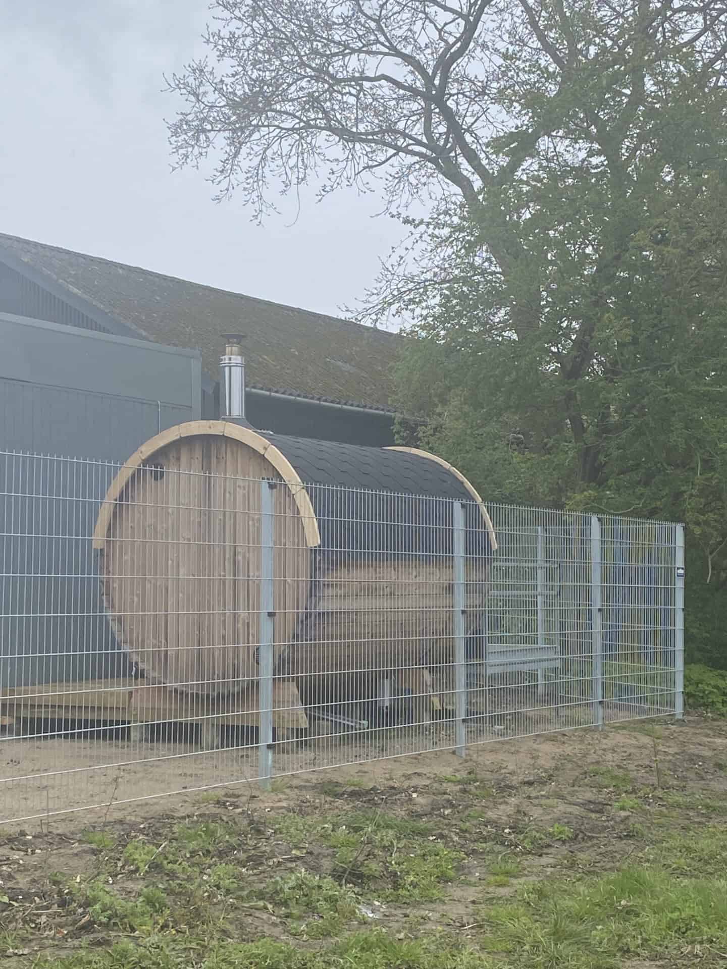 Gråt panelhegn foran et unikt buet træskur til opbevaring hos GA Teknik.
